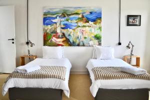 two beds in a room with a painting on the wall at B&B Petit-Hallet in Hannut