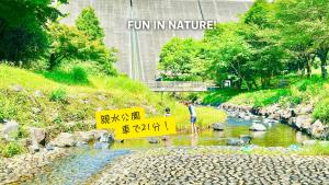 a man standing in a river with a sign that reads fun in nature at Sweet Loghome in Sano