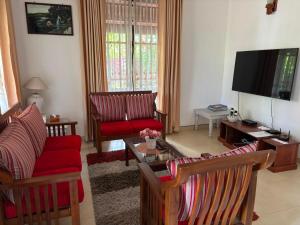 a living room with red chairs and a flat screen tv at Casa Winnie in Kelaniya