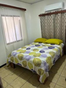 a bed with a quilt on it in a room at Buganvilla Quepos No 2 Aire acondicionado in Quepos