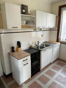 a kitchen with white cabinets and a sink and a stove at L'Authentique Jurassien in Champagnole