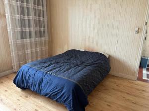 a bed with a blue comforter in a room at L'Authentique Jurassien in Champagnole
