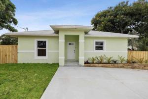 a small yellow house with a driveway at Palm Beach Cottage in West Palm Beach