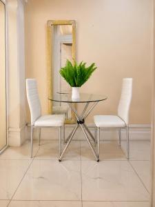 a dining room with a glass table and two white chairs at Tiah Whyte, Durban in Durban
