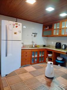 a kitchen with a white refrigerator and wooden cabinets at Quarto suite e sala no Centro in Nova Friburgo