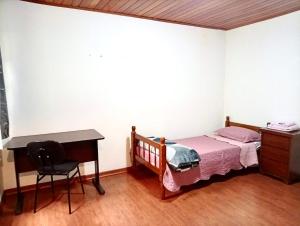 a bedroom with a bed and a desk and a desk at Quarto suite e sala no Centro in Nova Friburgo