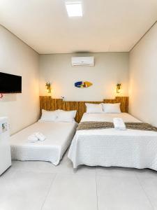 two beds in a room with a tv at Vista do Luar Corumbau in Prado +53 photos