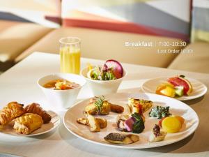 a table with three plates of food and a glass of orange juice at Hotel Intergate Kanazawa in Kanazawa