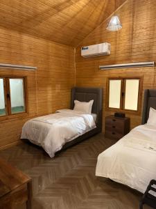 two beds in a room with wooden walls at اكواخ سمر in Abha