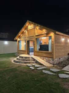a small wooden house with stairs in a yard at night at اكواخ سمر in Abha