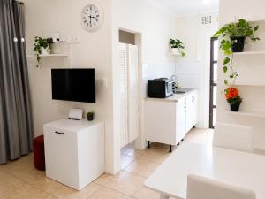 a living room with white furniture and a flat screen tv at Tiah Grey, Durban in Durban