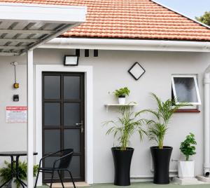 a white house with a black door and plants at Tiah Grey, Durban in Durban +1 photo