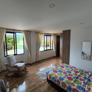 a bedroom with a bed and a chair and windows at Villa Conejo Miraflores in Chinauta +34 photos