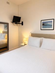a bedroom with a large white bed and a mirror at Pier Hotel Port Lincoln in Port Lincoln