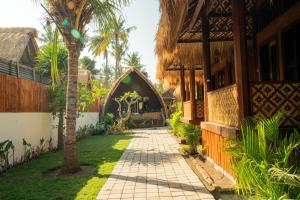 a walkway in front of a house with a palm tree at Welly Bungalow in Gili Trawangan