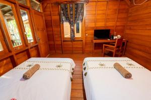 two beds in a room with a desk and a computer at Westwood Bungalow in Gili Trawangan