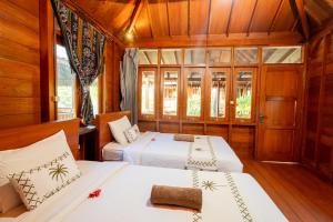 two beds in a room with wooden walls at Westwood Bungalow in Gili Trawangan