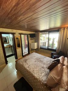 a bedroom with a large bed in a room with windows at Pousada Vertente das Águas in Lumiar