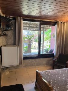 a bedroom with a bed and a large window at Pousada Vertente das Águas in Lumiar