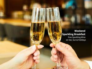 two people holding up glasses of white wine at Hotel Intergate Hiroshima in Hiroshima