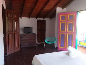 a bedroom with a bed and a door and a chair at Finca Hotel Mariangel in El Peñol