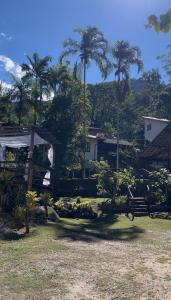 a garden with palm trees and a house in the background at Pousada Vertente das Águas in Lumiar