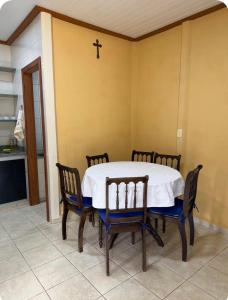 a dining room table with chairs and a cross on the wall at Aconchego Anjo Helena in Domingos Martins