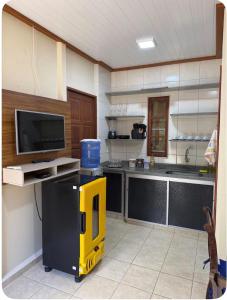 a kitchen with a tv and a yellow object in a room at Aconchego Anjo Helena in Domingos Martins +3 photos