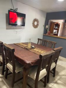 a dining room table with chairs and a tv on the wall at Tres Raíces in Miramar