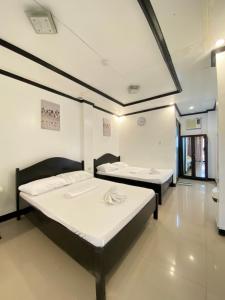 two beds in a room with white walls at Strangers Inn&Bar in General Luna