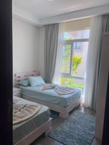 a bedroom with two beds and a window at العلمين الجديدة in El Dab‘a