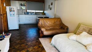 a living room with a leather couch and a kitchen at Marlo Tide Retreat in Marlo