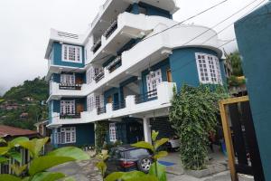 a blue and white building with a car parked in front at Monshing Homestay - Elevate your travel experience in Bomdila