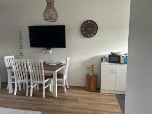 a dining room with a table and chairs and a clock at Coasters 27 in Sawtell