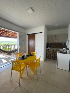a kitchen and dining room with a yellow table and chairs at Chalé Recanto da Coruja in Pão de Açúcar