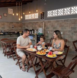 Eine Familie sitzt an einem Tisch und isst. in der Unterkunft Hotel Torre do Sal in Salinópolis