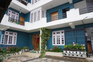 a blue house with white windows and plants at Monshing Homestay - Elevate your travel experience in Bomdila +12 photos