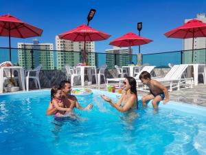 Eine Familie spielt im Swimmingpool eines Hotels in der Unterkunft Hotel Torre do Sal in Salinópolis
