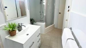 a white bathroom with a sink and a shower at Beachside at Gretel in Nelson Bay
