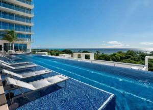 a swimming pool with lounge chairs next to a building at Sunset View Apartment Deluxe in Honolulu