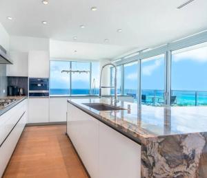 a kitchen with white cabinets and a view of the ocean at Sunset View Apartment Deluxe in Honolulu