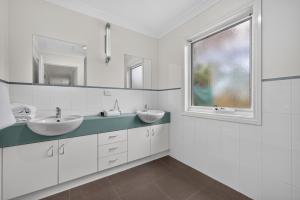 a white bathroom with two sinks and a window at Foreshore - Spacious Metung Escape in Metung +19 photos