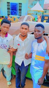 a group of three men standing next to a bed at RB Global Inc and RB Wizzy Ventures in Somanya