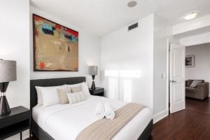 a bedroom with a white bed with two slippers on it at Luxurious 2BR 2BATH Condo Steps from Square One in Mississauga
