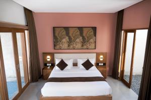a bedroom with a large bed with a painting above it at ME Villas Pererenan, Canggu in Canggu