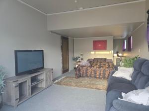 a bedroom with a bed and a flat screen tv at Affordable pit stop Te Horo Beach in Te Horo