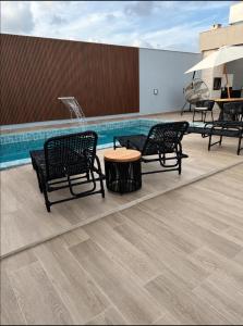 a pool with two benches and a table and an umbrella at Casa Aconchegante em Japaratinga in Japaratinga