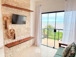 a living room with a tv and a large window at Roraimar Prime Maragogi - Beira Mar in Maragogi
