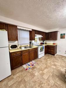 a kitchen with wooden cabinets and a white refrigerator at Downtown 2 BR Cottage Close to IU in Bloomington