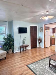 a living room with wooden floors and a white refrigerator at Downtown 2 BR Cottage Close to IU in Bloomington